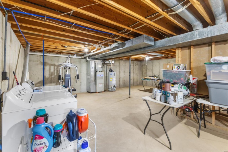 Unfinished basement featuring heating unit, washing machine and dryer, and water heater
