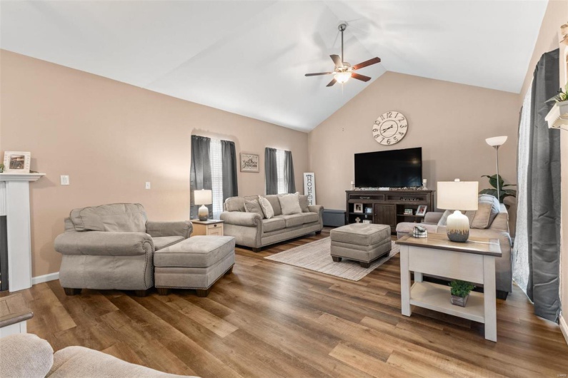 Living area with wood finished floors, a fireplace, lofted ceiling, and ceiling fan