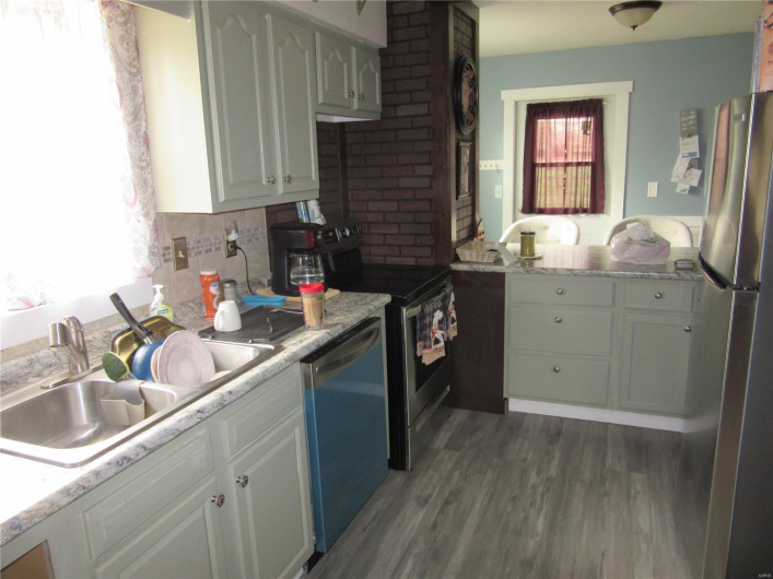 Kitchen featuring stainless steel appliances, decorative backsplash, a sink, dark wood-style floors, and white cabinets