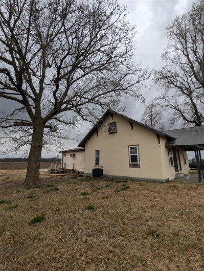 View of side of property featuring stucco siding, central air condition unit, and a yard