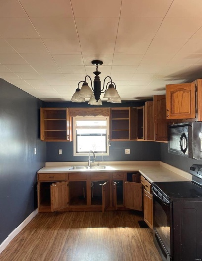 Kitchen with a sink, black appliances, open shelves, and wood finished floors