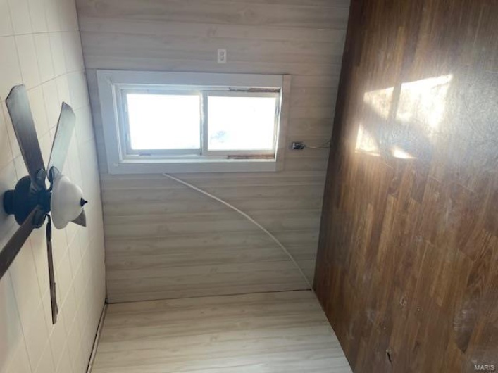 Unfurnished room featuring a paneled ceiling, wooden walls, ceiling fan, and wood finished floors