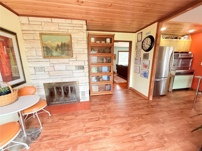 Living area with wooden ceiling, baseboards, a stone fireplace, and wood finished floors