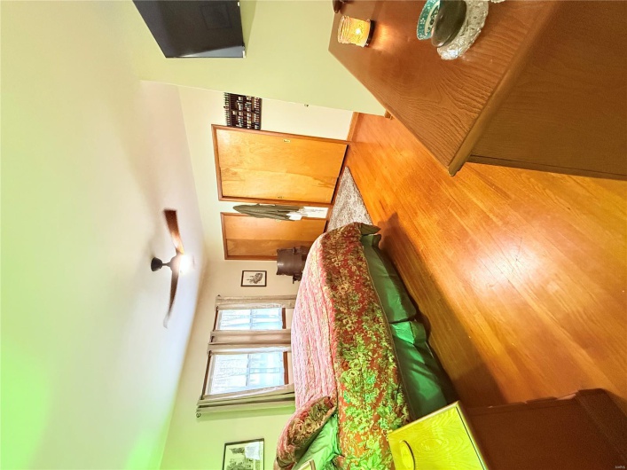 Bedroom with multiple closets, wood finished floors, and a ceiling fan