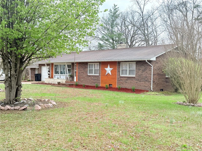 Ranch-style home with brick siding, a chimney, and a front lawn