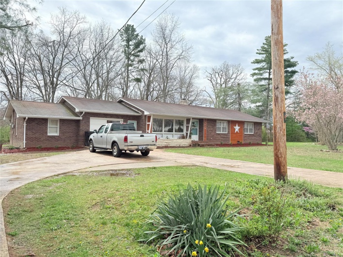 Ranch-style home with brick siding, driveway, a garage, and a front lawn