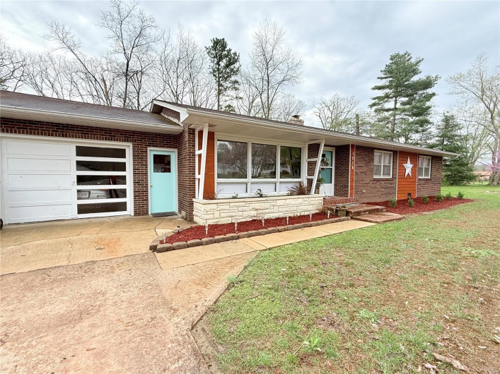 Ranch-style house with a chimney, a garage, concrete driveway, a front yard, and brick siding