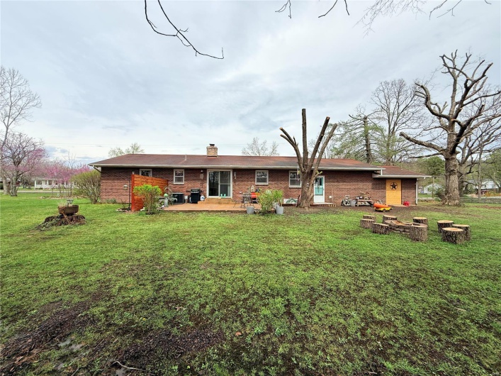 Rear view of house featuring a lawn, a chimney, a patio, and brick siding