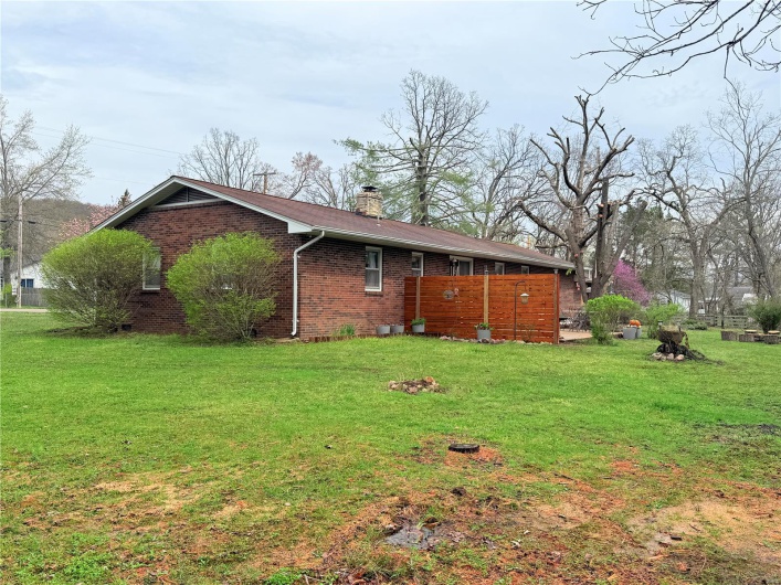 View of side of property featuring a chimney, brick siding, and a lawn