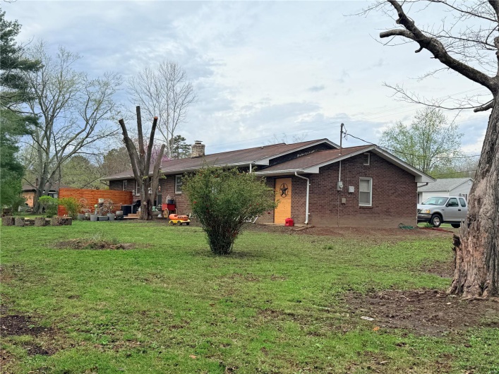 View of front of property featuring brick siding, a front yard, and a chimney