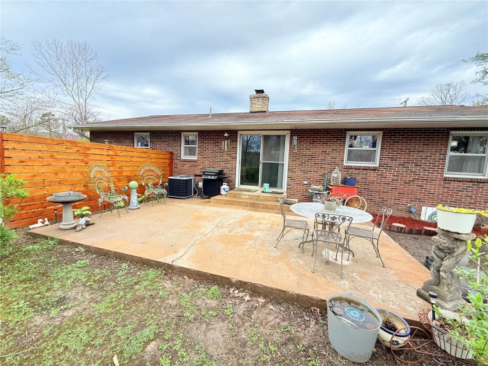 Back of house featuring brick siding, fence, a patio, and a chimney