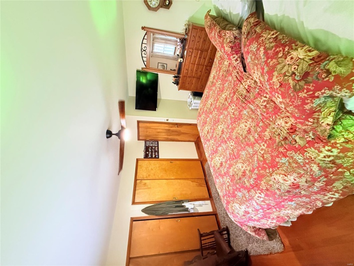 Bedroom featuring a ceiling fan, wood finished floors, and two closets