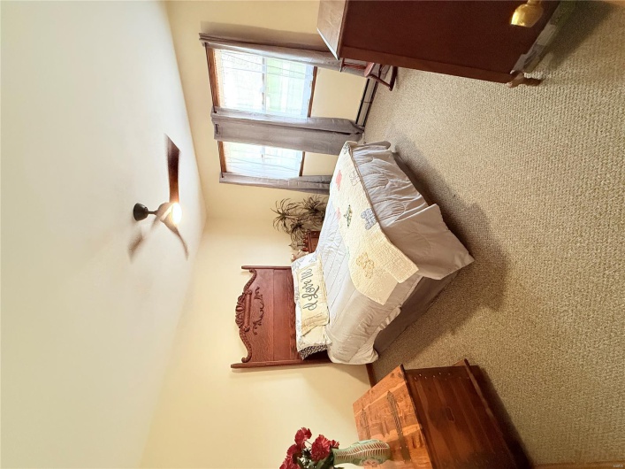 Bedroom with light colored carpet, a ceiling fan, and a baseboard heating unit