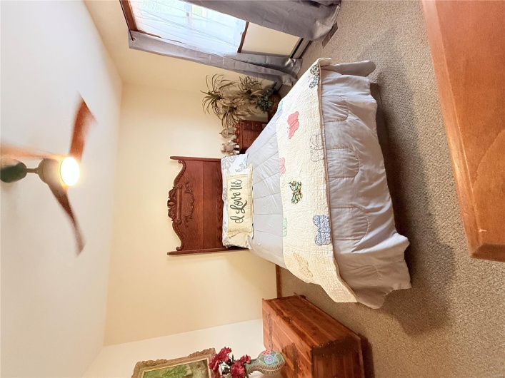 Carpeted bedroom featuring a baseboard heating unit and a ceiling fan