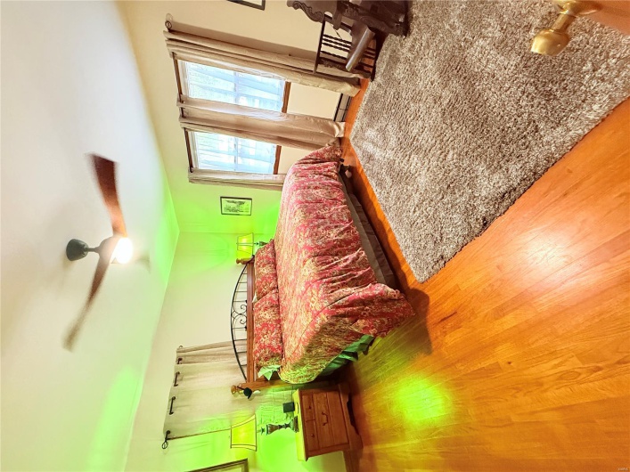 Bedroom with a baseboard radiator, wood finished floors, and ceiling fan