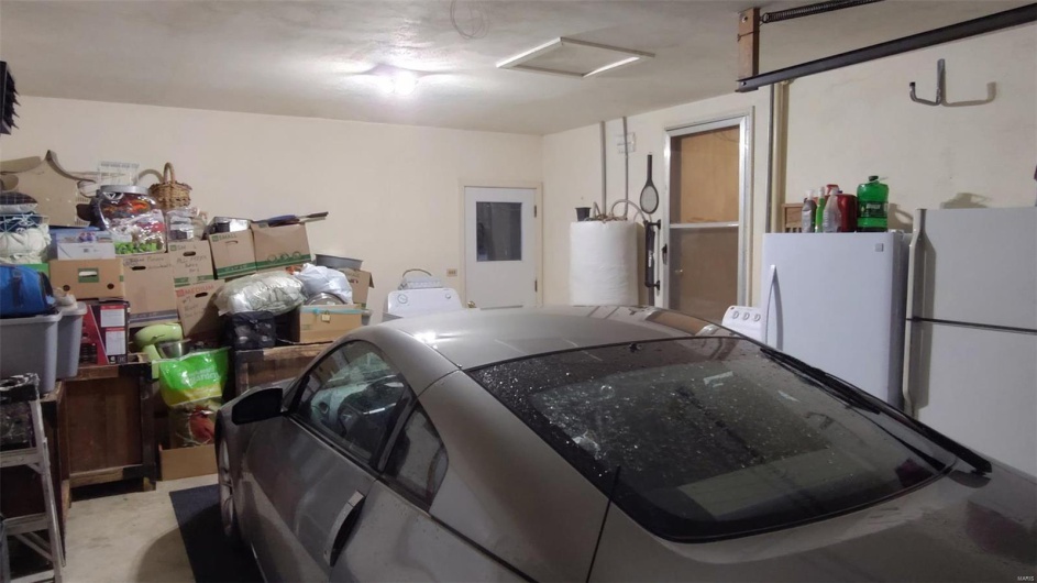 Garage featuring freestanding refrigerator and gas water heater