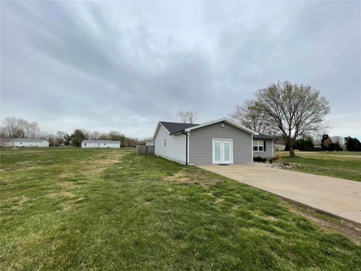 View of property exterior featuring a lawn, french doors, and concrete driveway