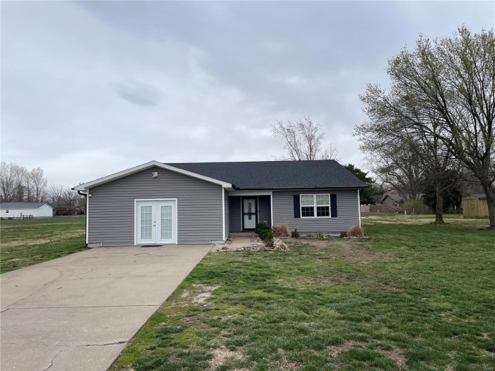 Single story home featuring roof with shingles, a front yard, french doors, and concrete driveway