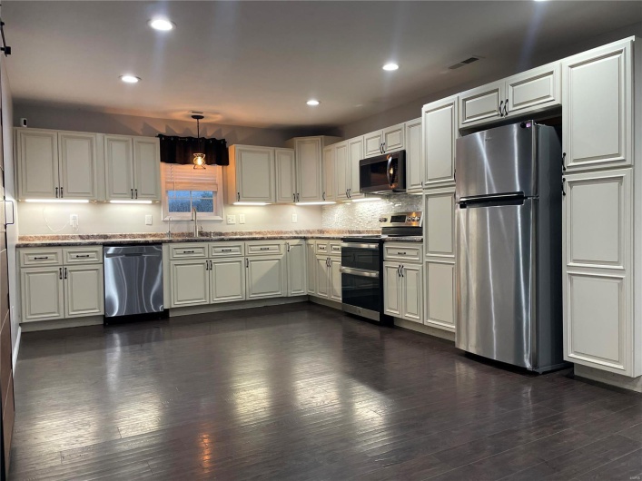 Kitchen featuring sink, stainless steel appliances, dark hardwood / wood-style flooring, and decorative light fixtures