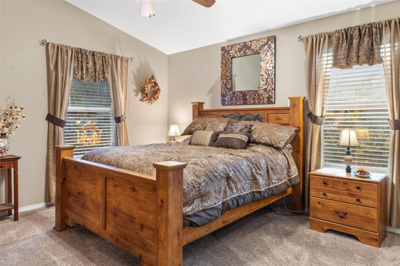 Bedroom featuring light colored carpet, vaulted ceiling, and ceiling fan
