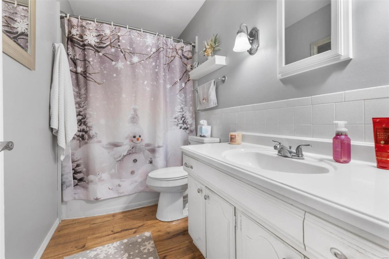 Full bathroom featuring vanity, toilet, wood-type flooring, and shower / tub combo with curtain