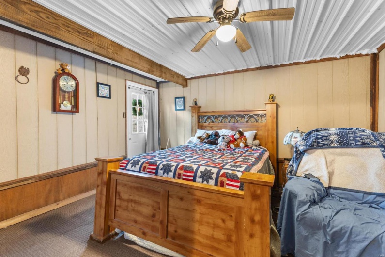 Bedroom with carpet flooring, ceiling fan, and wooden walls