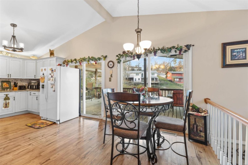 Dining area featuring vaulted ceiling with beams, light hardwood / wood-style floors, and an inviting chandelier