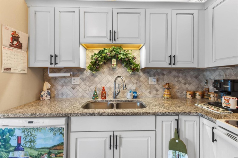 Kitchen featuring dishwashing machine, white cabinetry, sink, and tasteful backsplash