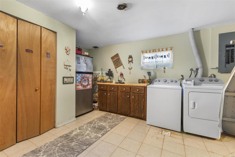 Laundry area with cabinets, light tile patterned floors, electric panel, and washer and dryer