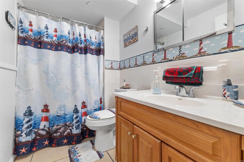 Bathroom featuring tile patterned floors, vanity, toilet, and tile walls