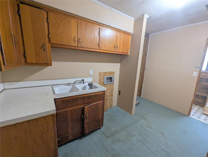 Washroom with hookup for a washing machine, a sink, ornamental molding, and cabinet space