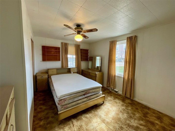 Bedroom featuring dark carpet, ceiling fan, multiple windows, and visible vents