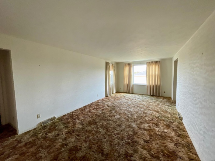 Carpeted empty room featuring visible vents