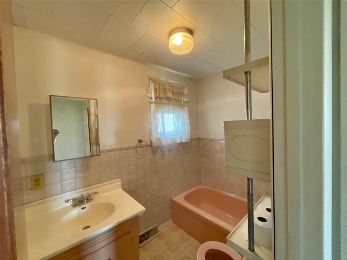 Bathroom featuring a bath, wainscoting, vanity, tile walls, and visible vents