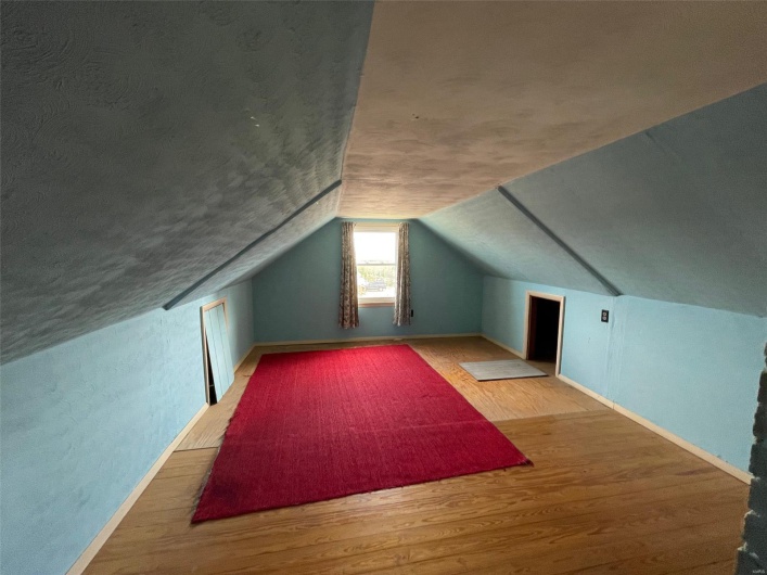 Bonus room featuring vaulted ceiling, baseboards, and wood finished floors