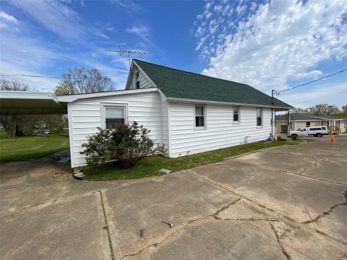 View of side of property with a carport and a shingled roof