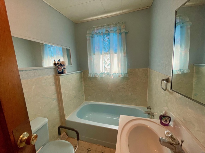 Bathroom with tile walls, a garden tub, tile patterned flooring, and toilet