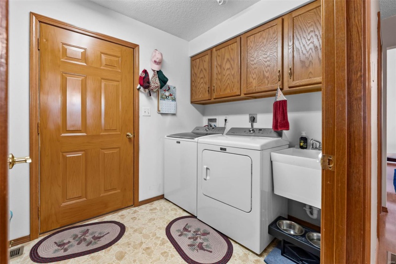 Laundry room featuring baseboards, a textured ceiling, washing machine and clothes dryer, cabinet space, and a sink
