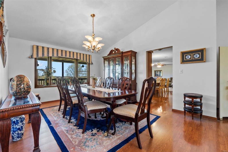 Dining space with wood finished floors, high vaulted ceiling, baseboards, and ceiling fan with notable chandelier