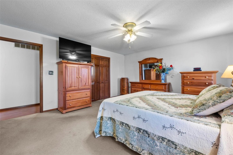 Bedroom with visible vents, ceiling fan, light carpet, and a textured ceiling
