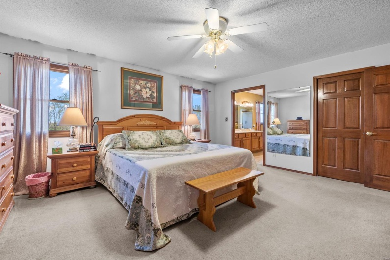 Bedroom with light carpet, ensuite bath, a textured ceiling, and a ceiling fan