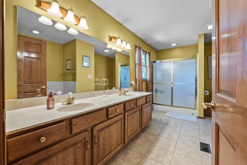 Bathroom with a shower stall, a textured ceiling, a sink, and tile patterned flooring