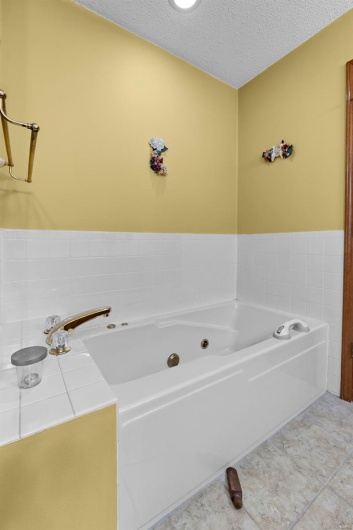 Full bathroom featuring a tub with jets and a textured ceiling
