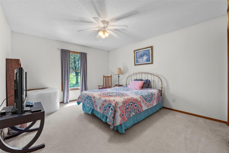 Carpeted bedroom featuring a textured ceiling, baseboards, and a ceiling fan