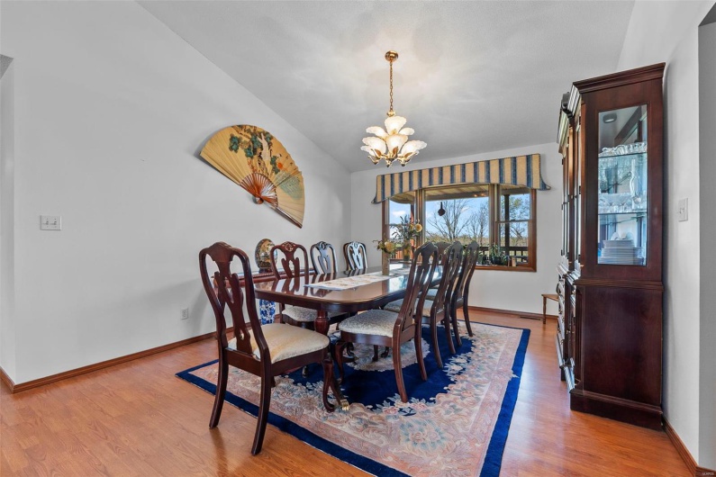 Dining space with lofted ceiling, baseboards, an inviting chandelier, and wood finished floors