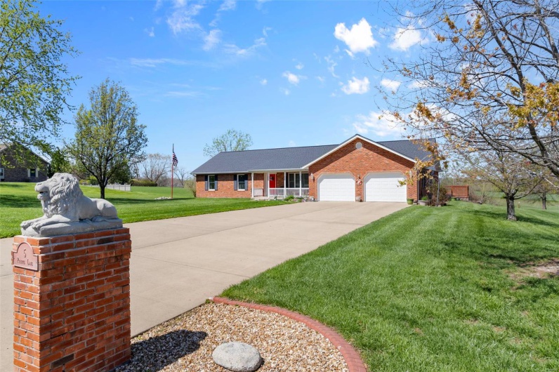 Ranch-style home featuring a front yard, brick siding, driveway, and an attached garage