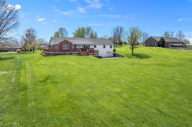 Rear view of property with a deck and a lawn