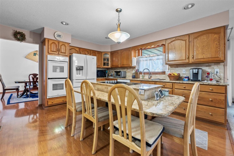 Kitchen featuring white appliances, light wood-style flooring, a kitchen bar, and brown cabinetry