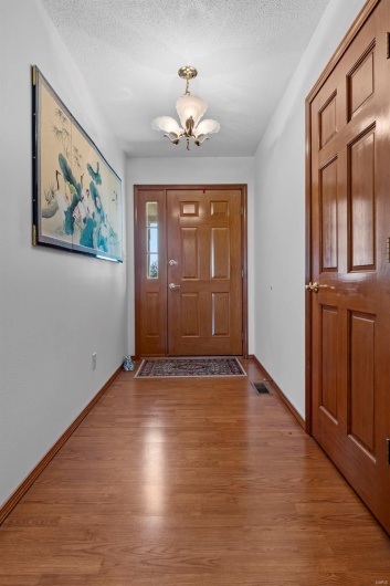 Entryway featuring visible vents, an inviting chandelier, wood finished floors, and a textured ceiling