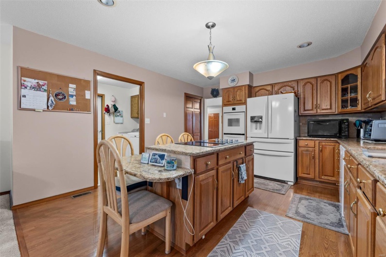 Kitchen featuring brown cabinetry, wood finished floors, black appliances, and a kitchen island